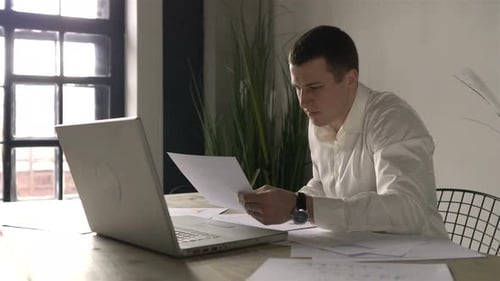 Man Reads Paperwork at Office Desk