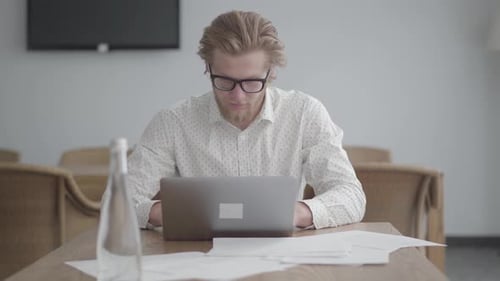 Porträt Nachdenklicher Geschäftsmann in Brille sitzt am Tisch in einem hellen, komfortablen Büro