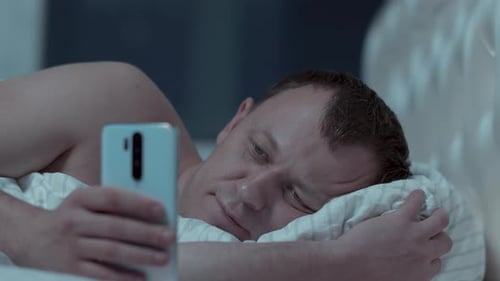 Adult Uses Phone Lying in Bed at Night