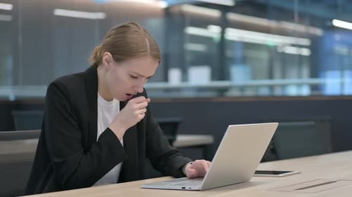 Woman Coughing While Working at Laptop in Office