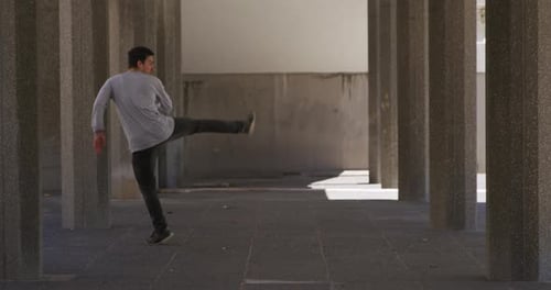 Young Man Practicing Capoeira Moves in Urban Setting