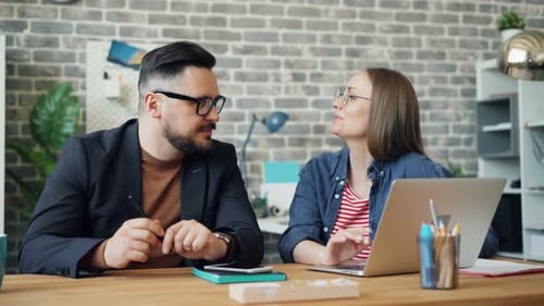 Man and Woman Collaborating on a Laptop in Office