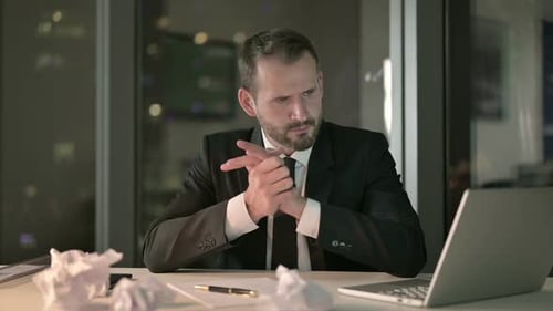 Upset Businessman Looks Stressed on Office Desk at Night