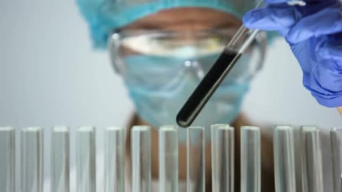Scientifique marquant les tubes à essai avec la substance noire, commandant la réaction chimique