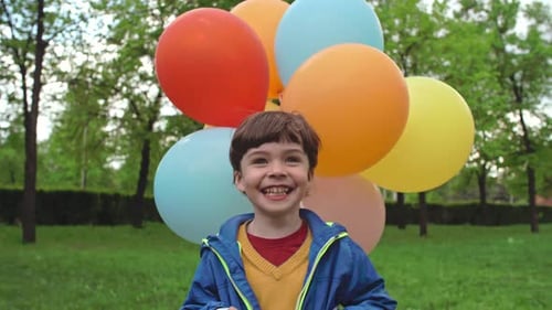 Ekstatischer kleiner Junge mit Luftballons