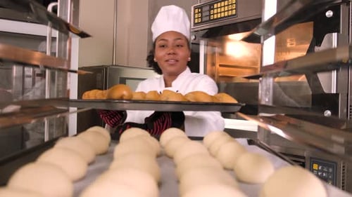 Smiling Woman Baker Takes Bread from Oven