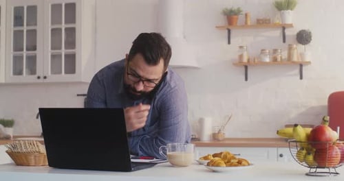 Man Working at Home Eating Croissants