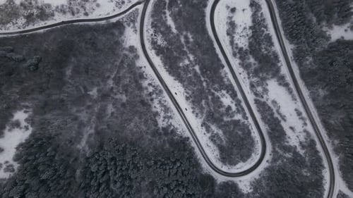 Aerial View of a Serpentine Road Goes Through Snowy Forest in Carpathian Mountains Winter Time