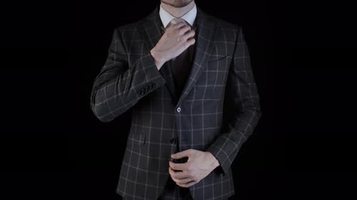 Man Adjusting Tie in Dark Checkered Suit