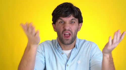 Angry Irritated Young Man Isolated on Yellow Background in Studio