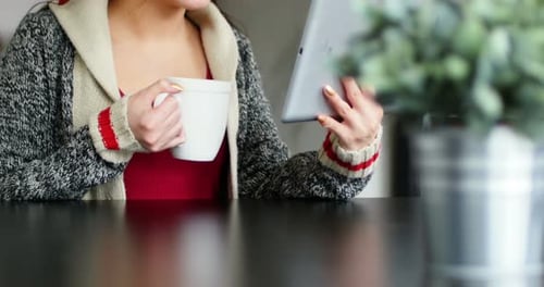 Woman Drinking Coffee Using Tablet at Table