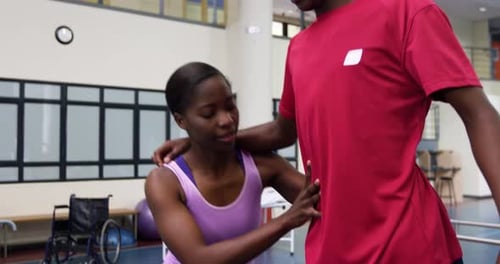 Physical Therapist Helping Man with Prosthetic Blades Practice Walking