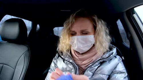 Young Woman Puts on Mask and Gloves in Car