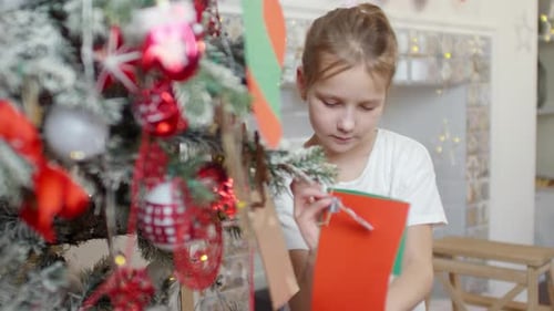 Child Decorates Christmas Tree with Paper Ornaments