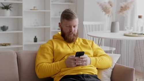 Man Relaxing on Couch Using Smartphone