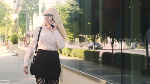 Woman Talking on Phone Walking Down City Street