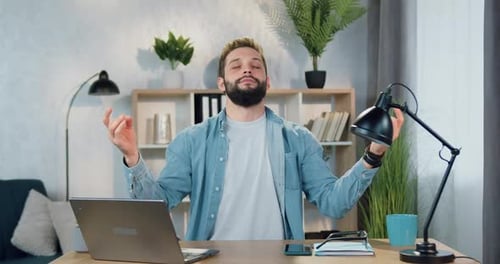Bearded Man Meditating at Desk in Modern Office