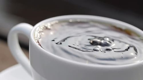 Zeitlupe mit dem letzten Tropfen des Kaffees fällt in die Tasse