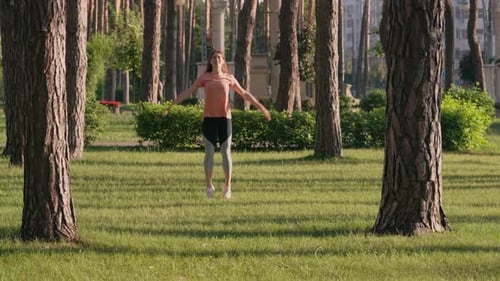 Woman Doing Jumping Jacks in a City Park