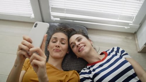 Top view of two girls taking selfie on the floor. Shot with RED helium camera in 8K