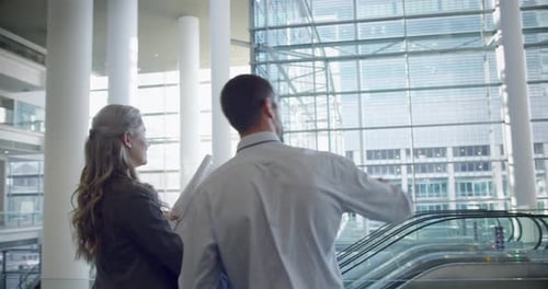 male and female architects discussing over blueprint in office 4k