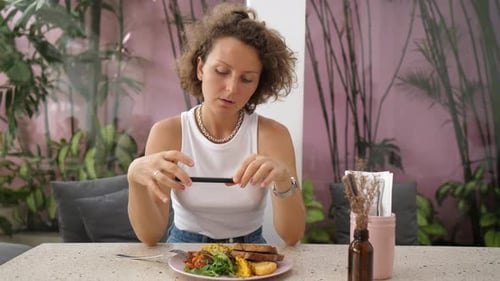 Woman Taking Picture of Food at Cafe