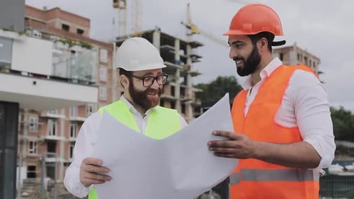 Two Smiling Men Looking at Building Blueprints