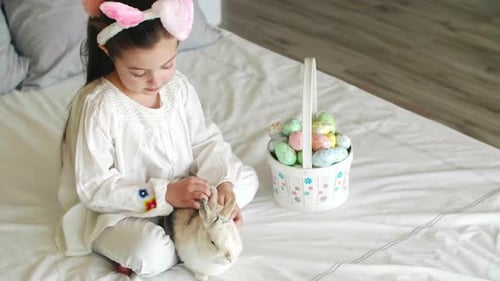 Girl Pets Rabbit with Easter Basket and Eggs