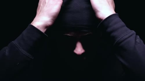 Person in Balaclava Puts on Mask and Holds Gun