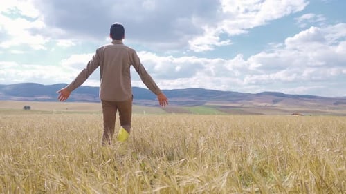 Farmer walking in wheat field.