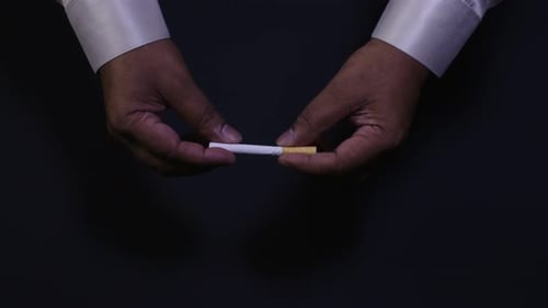 Des mains cassent une cigarette