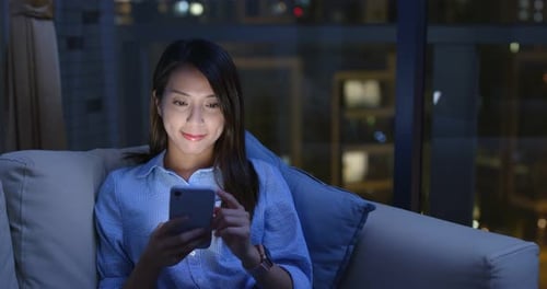 Woman Using Smartphone at Night in Urban Home