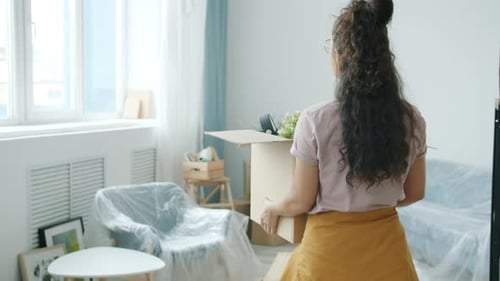 Woman Carries Moving Box in Bright Room