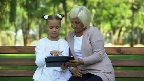 Grandmother and Granddaughter Using Tablet in the Park