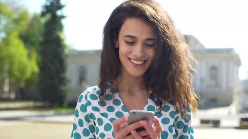 Woman Using Smartphone in Urban Setting, Smiling