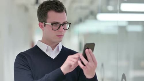 Young Man Using Smartphone in Modern Office