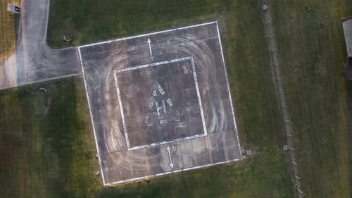 Luftaufnahme eines leeren Hubschrauberlandeplatzes oder Hubschrauberlandeplatzes auf dem Feld während des Tages - Umlaufbahn und Landung