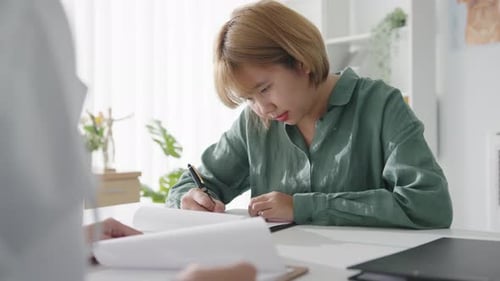 Asian female patient signing medical form or signature health insurance agreement in hospital