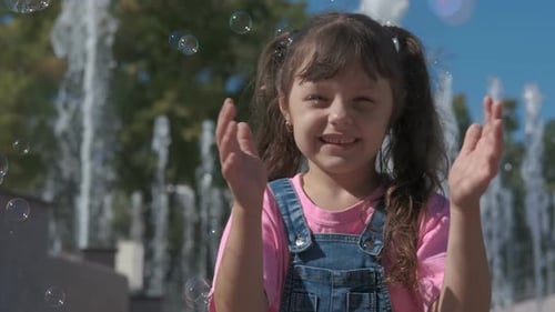 Happy Child Playing with Soap Bubbles by Fountain