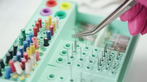 Dentist Inspecting Dental Instruments With Tweezers