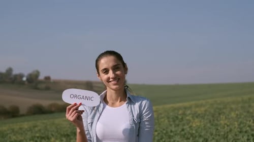 Girl Stands On The Field With Inscription ORGANIC
