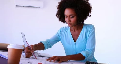 Female architect working on blueprint over drafting table 4k