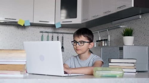Das Kind, das der Schüler lernt, zu Hause zu sein und in der Küche am Tisch zu sitzen