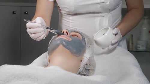 Concepto de belleza femenina. Mujer joven recibe una máscara facial que mejora la piel del rostro. Mujer atractiva descansando