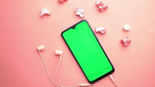Top View of Smart Phone Ear Phone and Popcorn on Pink