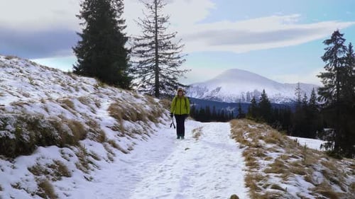 Woman Hiking Snowy Mountain Path on Cold Day