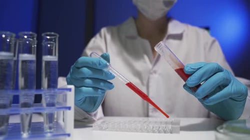 Lab Worker Drops Red Liquid Into Testing Tray
