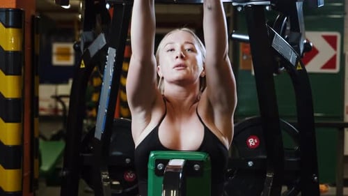 Young woman pulling the trainer in gym, doing exercise on her workout.