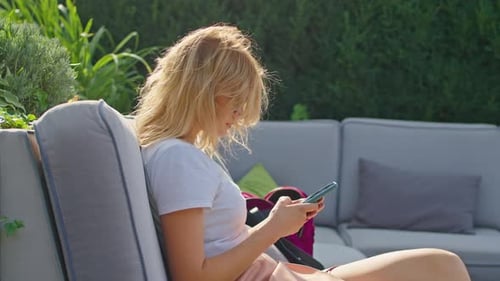 Young Woman Enjoys Talking on the Phone Texting with Someone in a Wonderful Place Sitting in a White