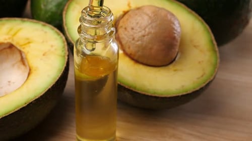 Avocado oil with avocado fruit on wooden table. Avocado is a highly nutritious fruit.